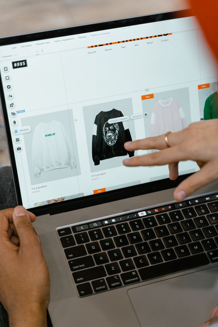 who-we-are Close-up of hands interacting with a shopping website on a laptop screen indoors.